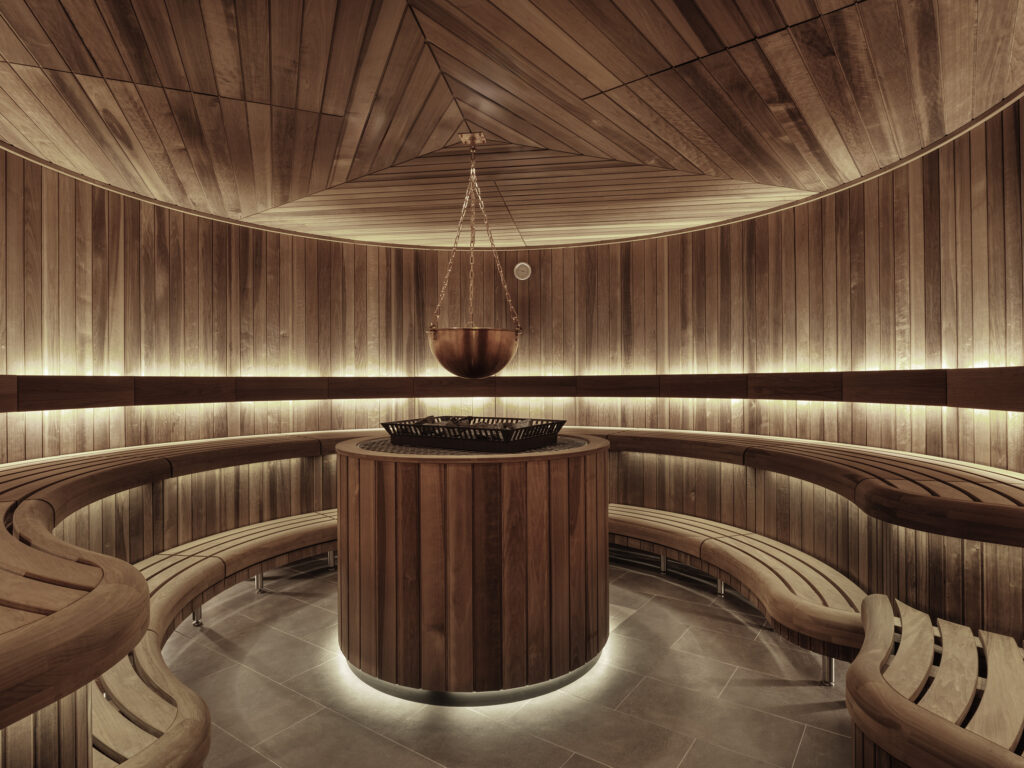Ett runt basturum täckt i trä med ett runt bastuaggregat i mitten av rummet. 