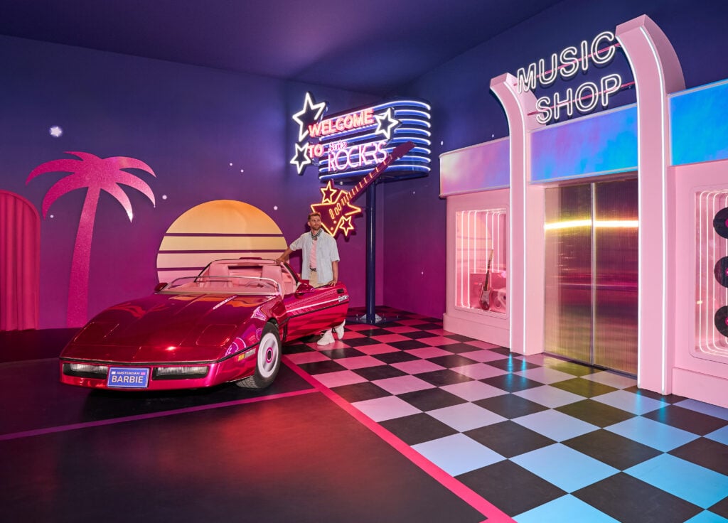 En rosa Barbiebil i stort format, schackrutigt golf, färgglada väggdekorer.