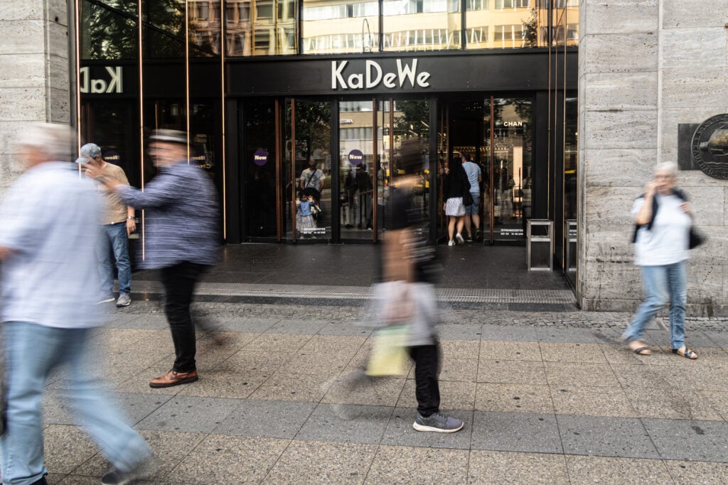 Människor susar förbi utanför en stor entré till ett varuhus. 