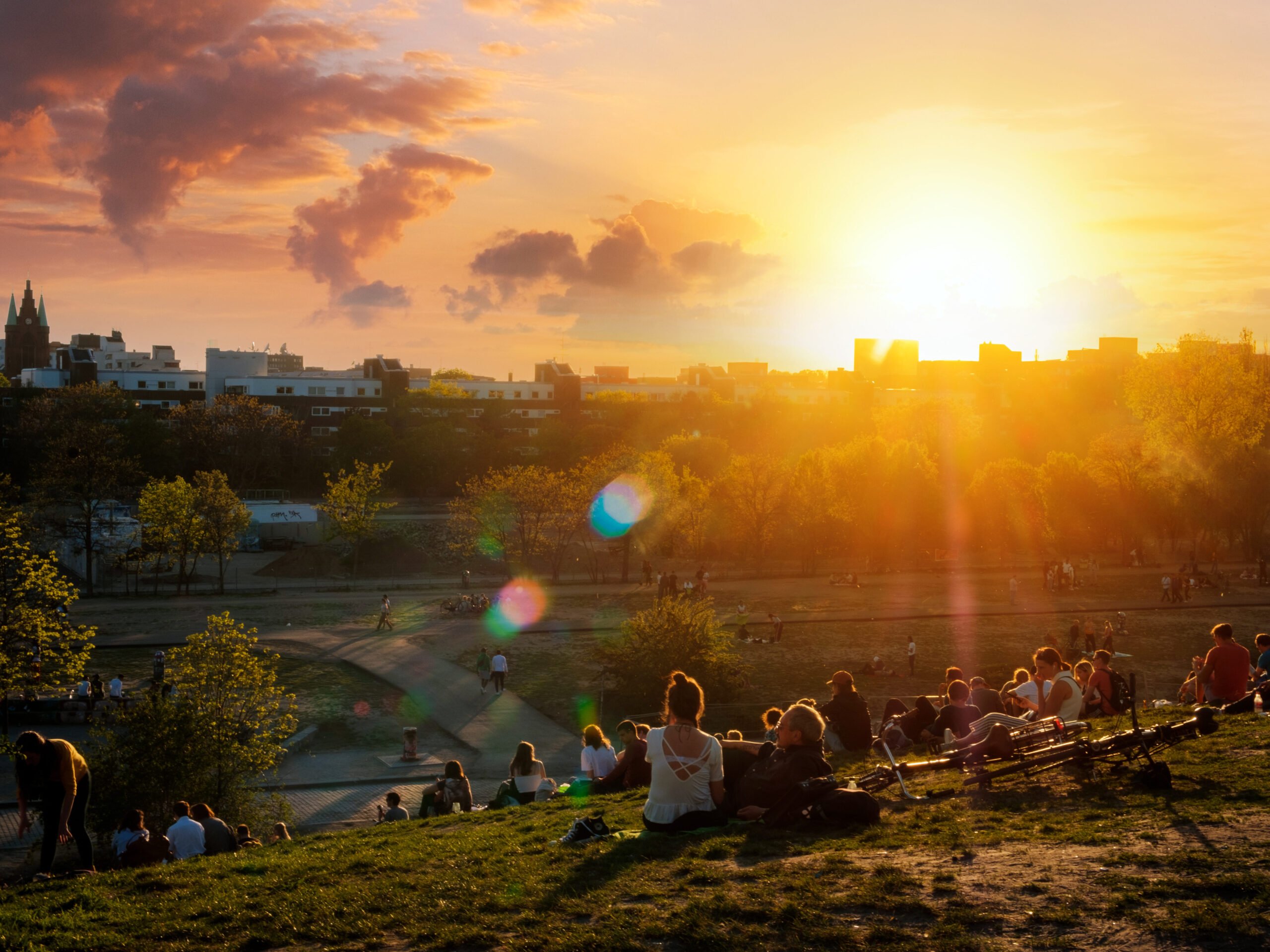 People enjoying view on sunset sky over skyline from public park (Mauerpark) on summer day in Berlin