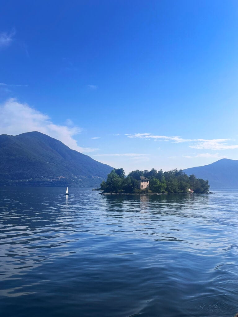 En vacker sjö med en lummig liten ö i mitten, med ett hus på Berg i bakgrunden. 