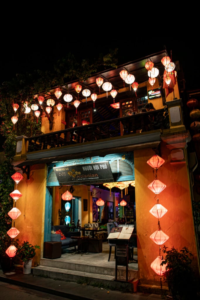 En gul fasad i mörkret, upplyst av röda papperslyktor. 