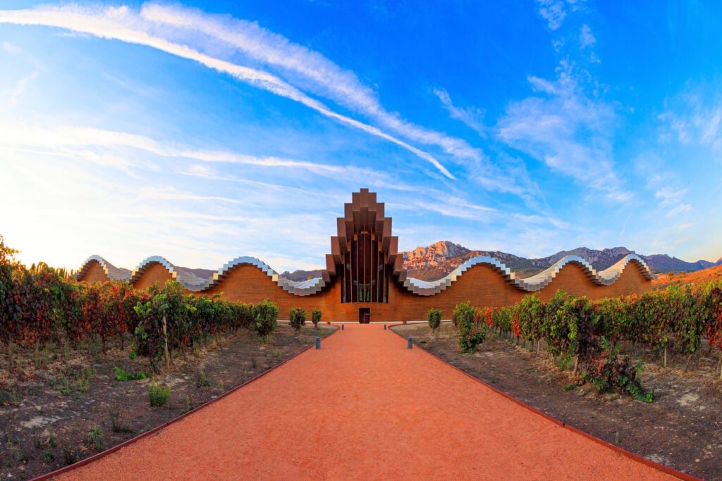 The magnificent modern architecture of Bodegas Ysios. Bright flaming colors of the sunset. Journey to the warm Spanish autumn. Fantastic beauty.