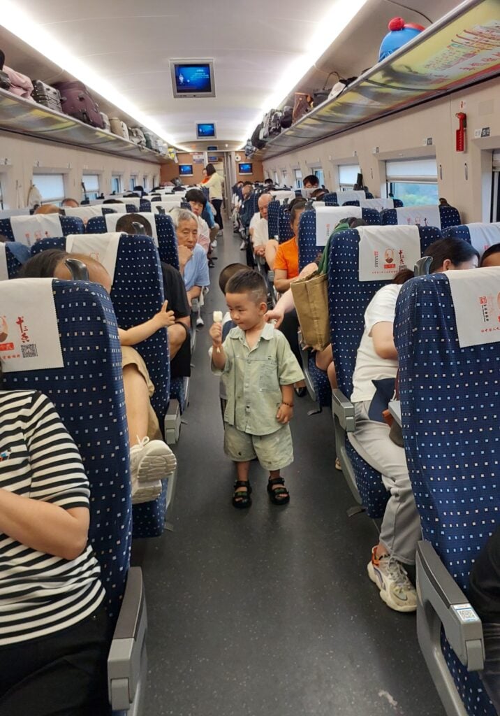 Liten pojke som går i tågkorridor.