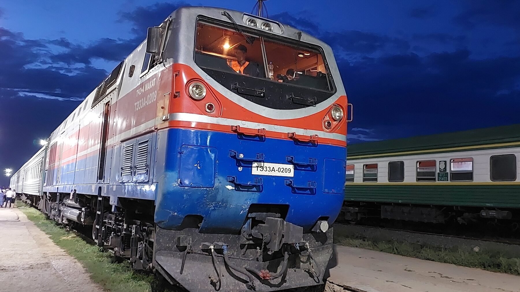 Blått och rött tåg i kvällsljus.