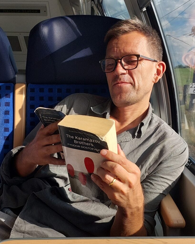 Man som läser bok på tåg.