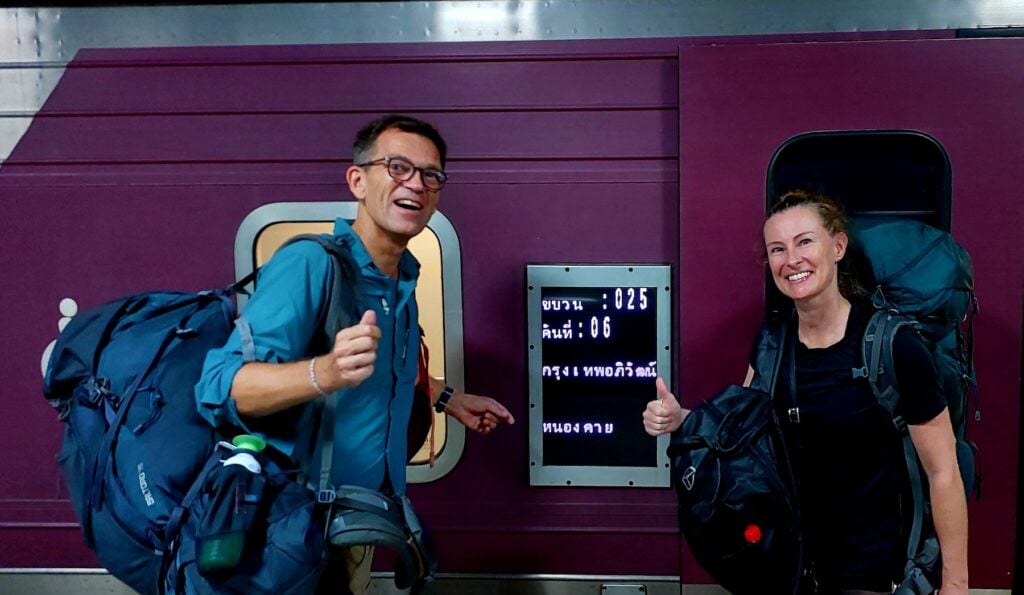 Man och kvinna med ryggsäckar framför tåg.