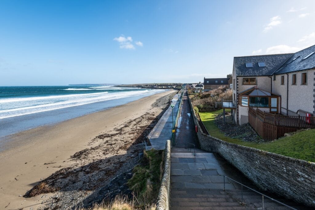 Vita hus vid sandstrand vid hav.