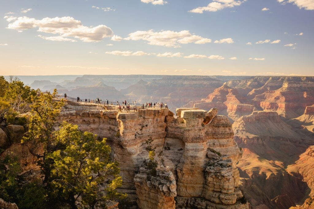 Ett dramatiskt klipplandskap med turister som promenerar högst upp på en platt klippa.