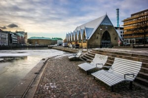 En vacker, kyrkliknande byggnad vid vattnet, på kajen står stora härliga träsoffor.