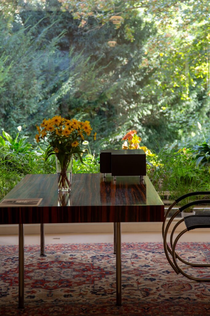Bord med blomvaser och utsikt mot trädgård.