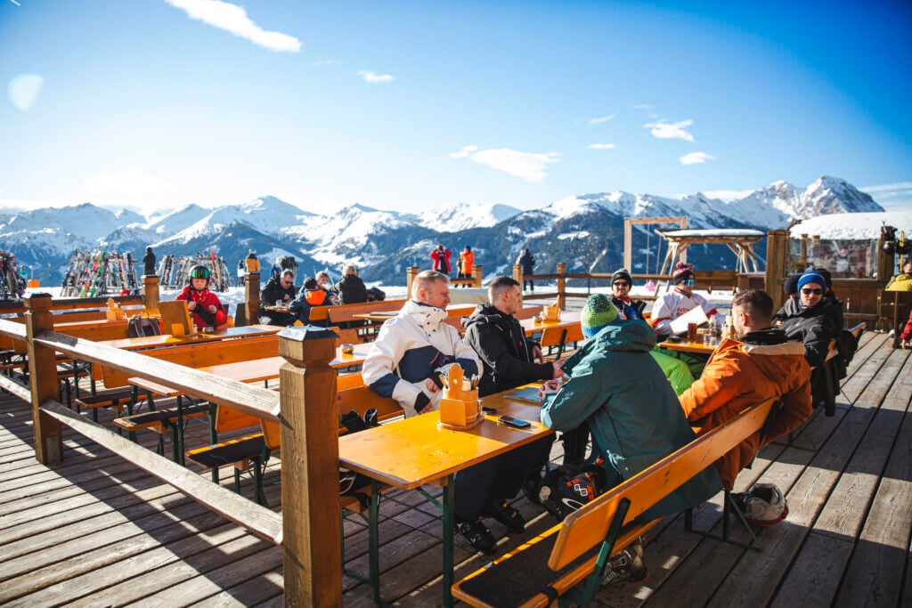 SKidåkare njuter av solgasset på en uteservering mitt bland Alptopparna. 