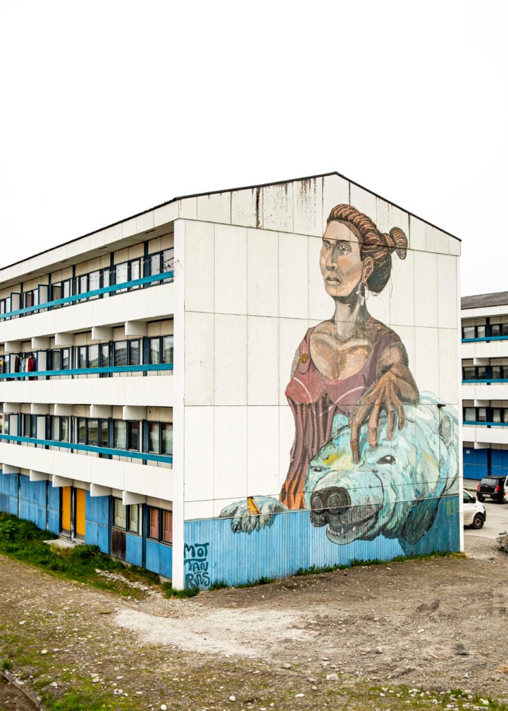 Ett grått hyreshus med en färgglad muralmålning över hela fasaden. 