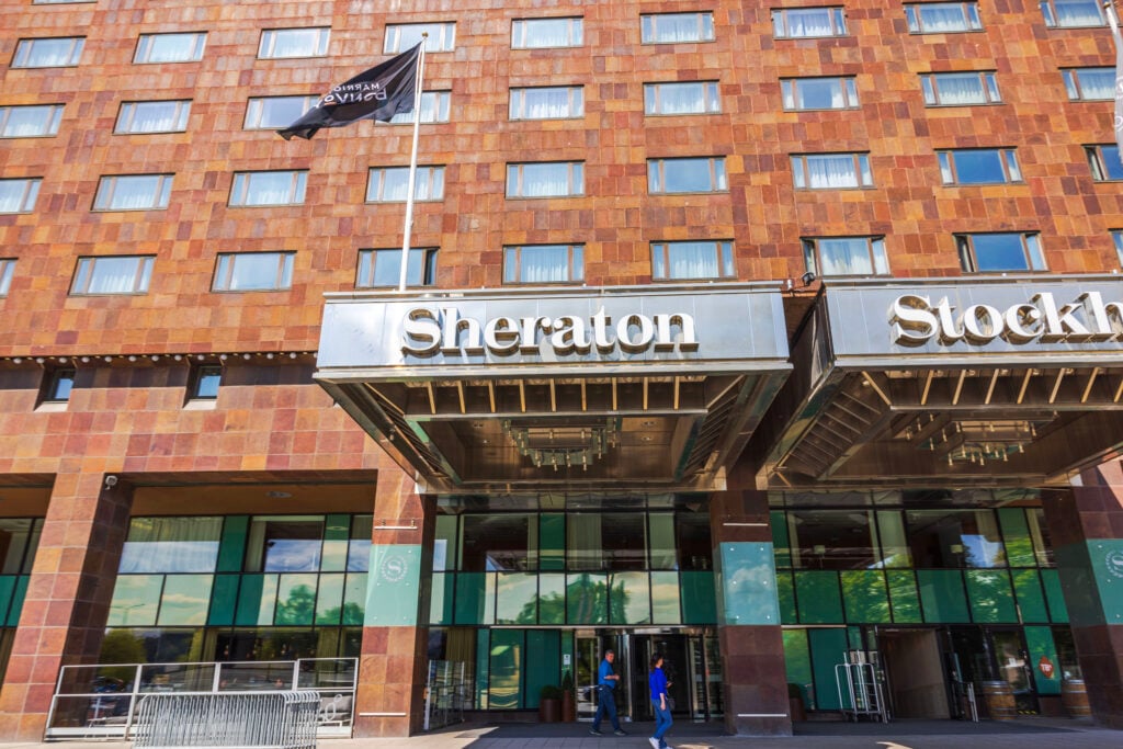 En röd hotellfasad med en entré som det står Sheraton på.