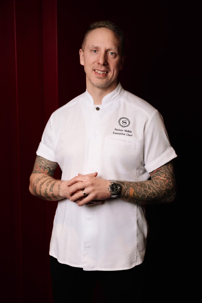 En man i vit kockskjorta poserar för kameran.