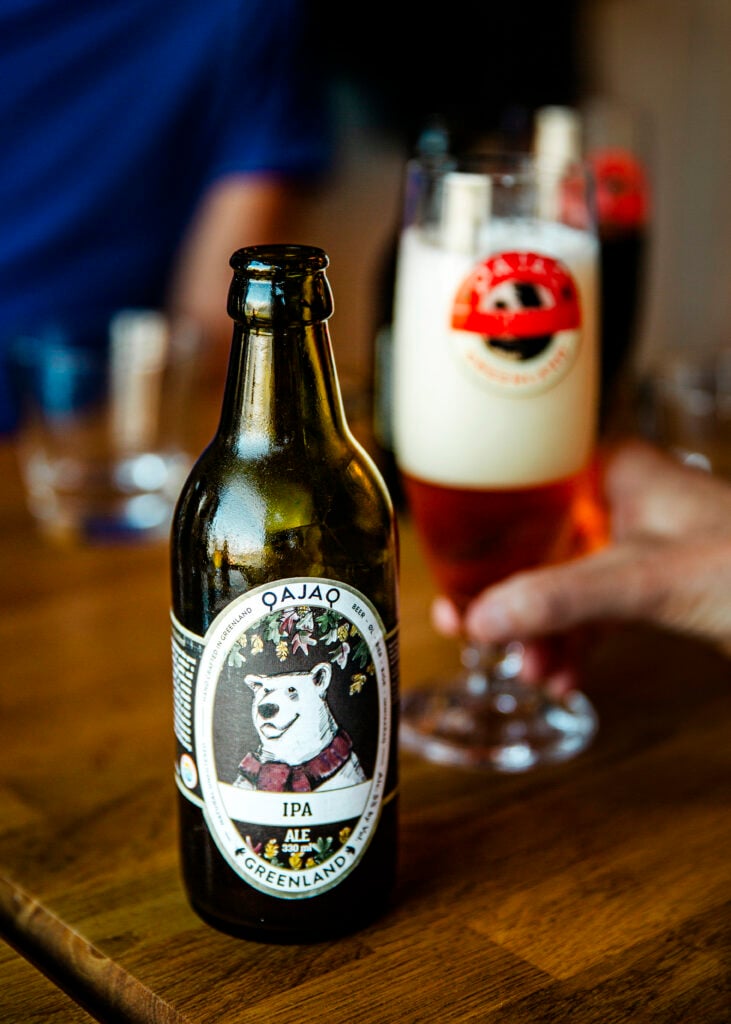 En ölflaska bredvid ett upphällt ölglas.