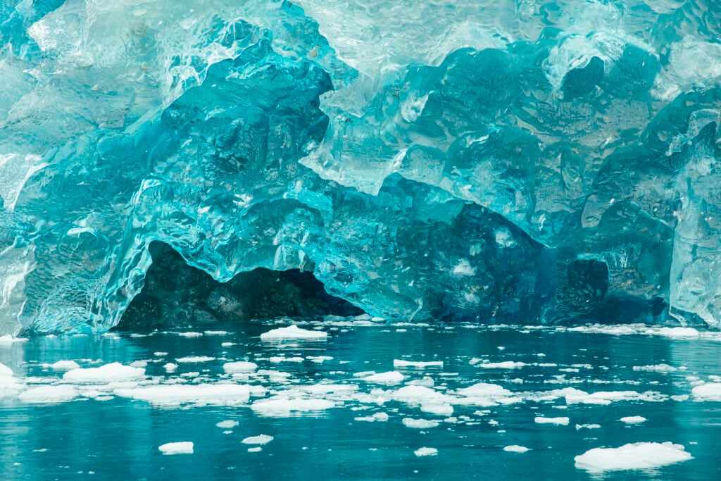 Turkosblå is fyller bilden. Små vita isblock flyter runt i havet.