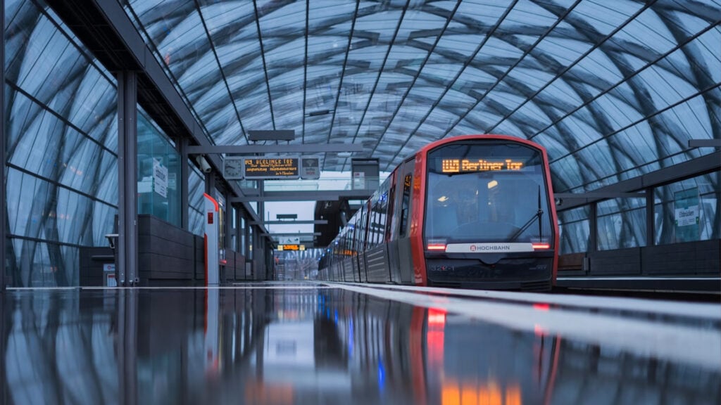 Ett rött tåg står på en perrong under ett välvt glastak.