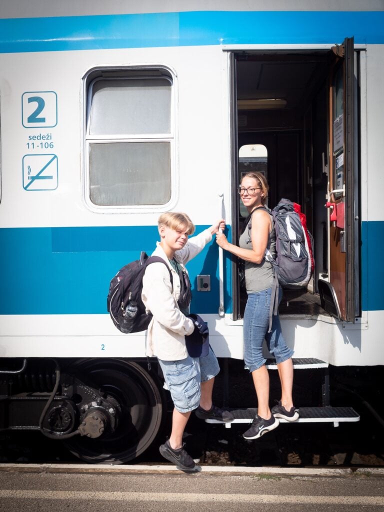 Barn och mamma med ryggsäckar som kliver ombord på tåg.