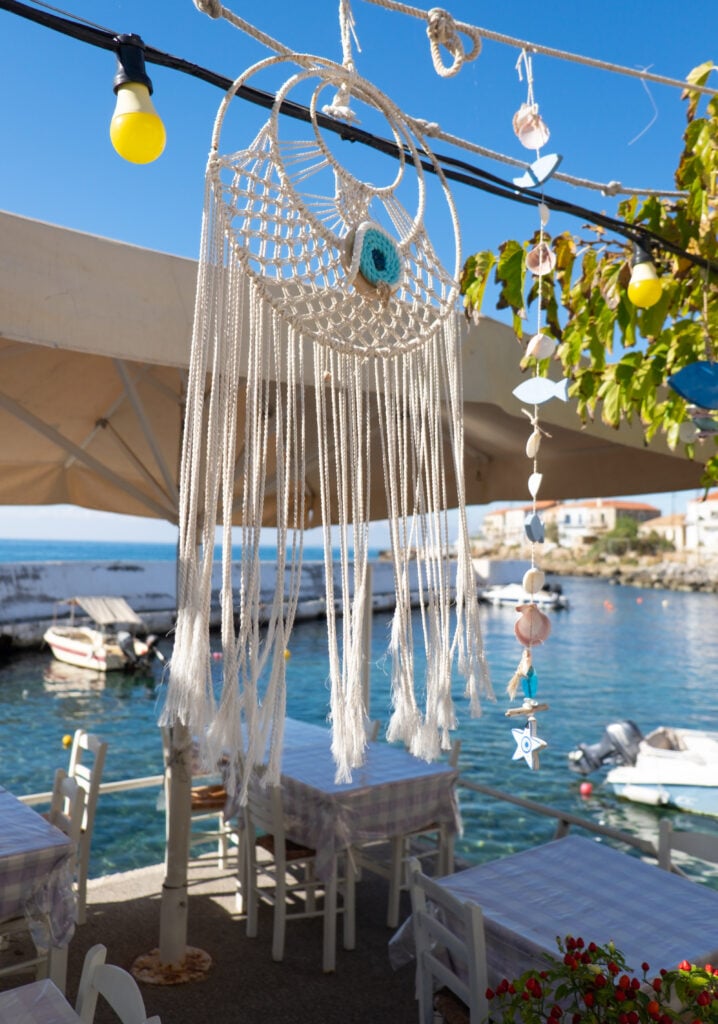 En drömfångare hänger under ett soltak på en servering. Blått hav.