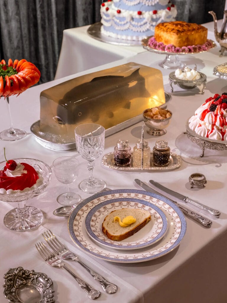 Ett dukat bord med en fisk i gelé och en smörgås med en smörsvan. 