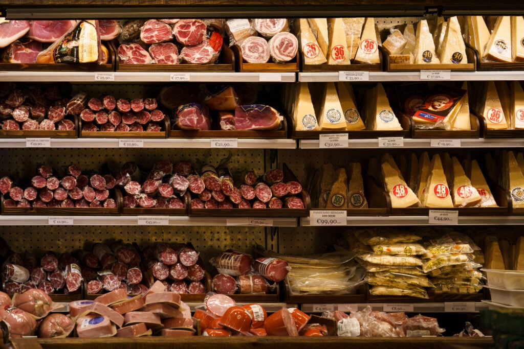 Kyldiskar med charkuterier och parmesanostar, fyra hyllor fyllda.