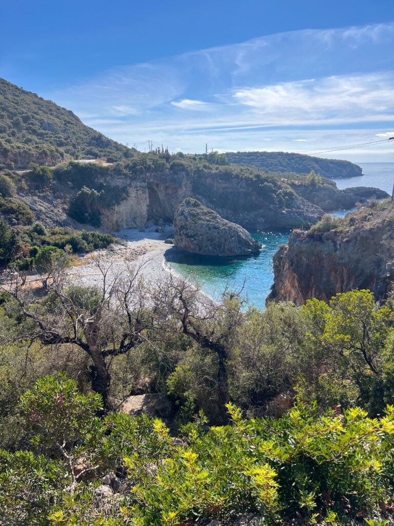 En översiktsbild över strand och blått vatten, träd omgärdar stranden. 