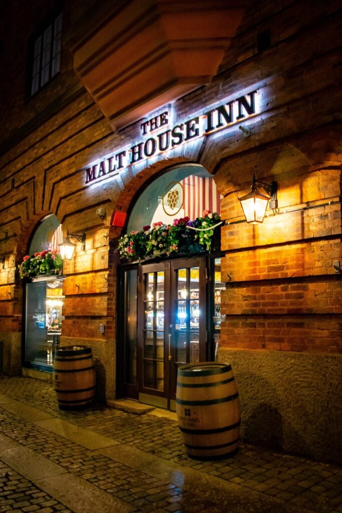 I mörkret syns en upplyst pubdörr med hotellnamnet ovanför. 