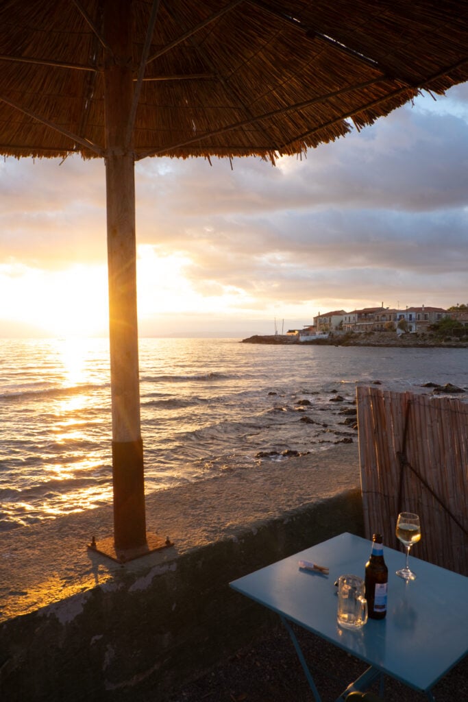 Ett dukat bord med ölglas på ett bord framför stranden i solnedgången. 