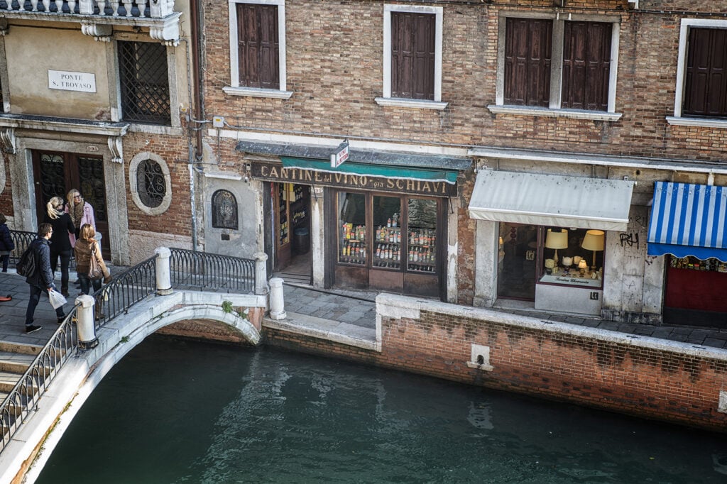 En vy ovanifrån på en restaurangfasad i sten ovanför en kanal med en stenbro. 