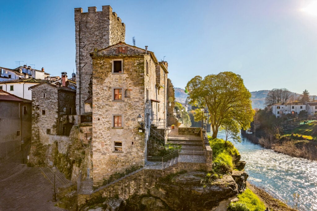 En medeltida by ligger bredvid en fors. Solen strålar.