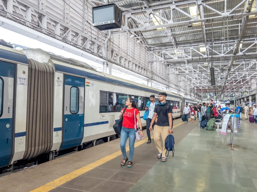 Indiska resenärer på perrongen bredvid modern snabbtåg.