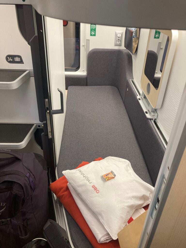 Nattågskorridor med två personer som gör sig redo för natten.