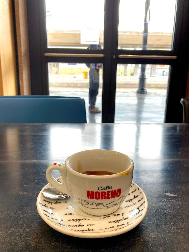 Kaffekopp på bord med perrong i bakgrunden.