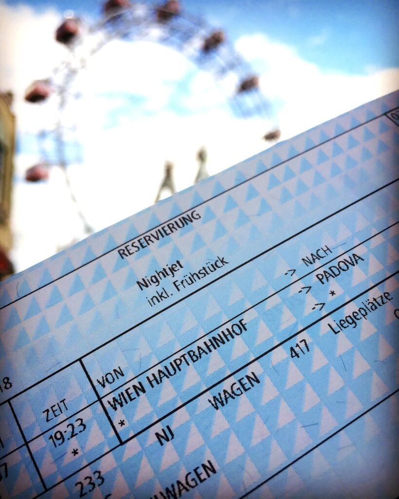 Nattågsreservationsbiljett i förgrunden, pariserhjul i bakgrunden.