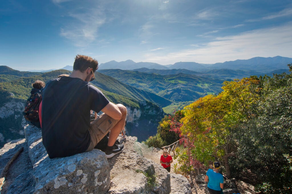 Människor rastar på en bergstopp med makalös utsikt över vida berg.