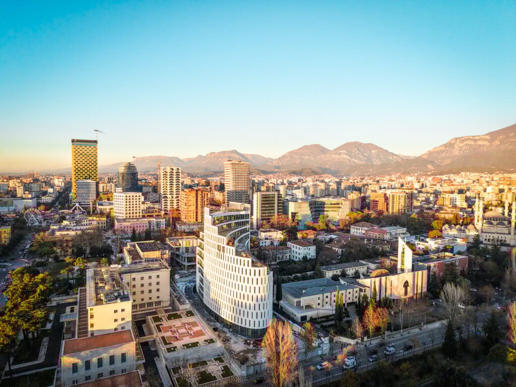 En storstad i solnedgång, med ett bergslandskap bakom.
