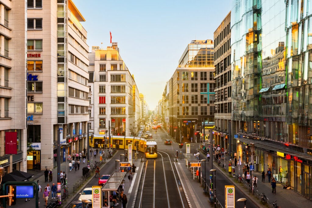 Solen sänker sig mellan skyskraportna, en gul spårvagn slingrar sig fram på gatorna. 