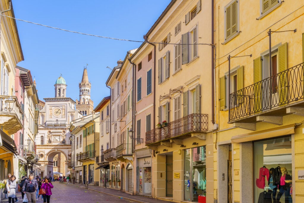En äldre stadsgata med mysiga små hus och personer som går på gatan. Blå himmel. 