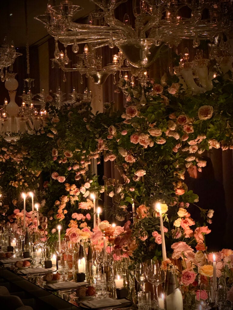Ett dukat långbord med ljus, massor av vinglas, taget överdådigt dekorerat med sidenrosor. 