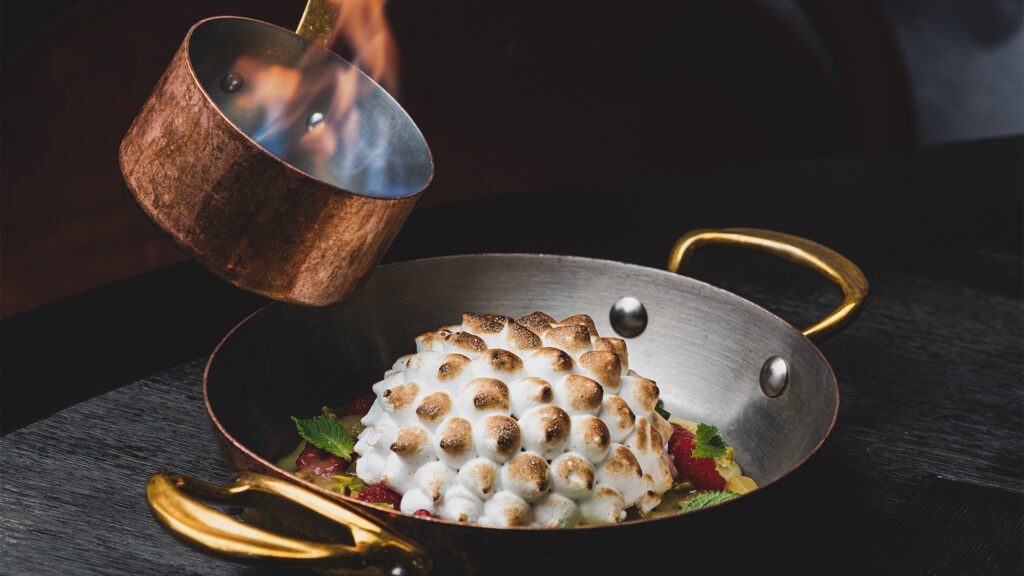 En brinnande gryta hälls över en avbränd marängbakelse.