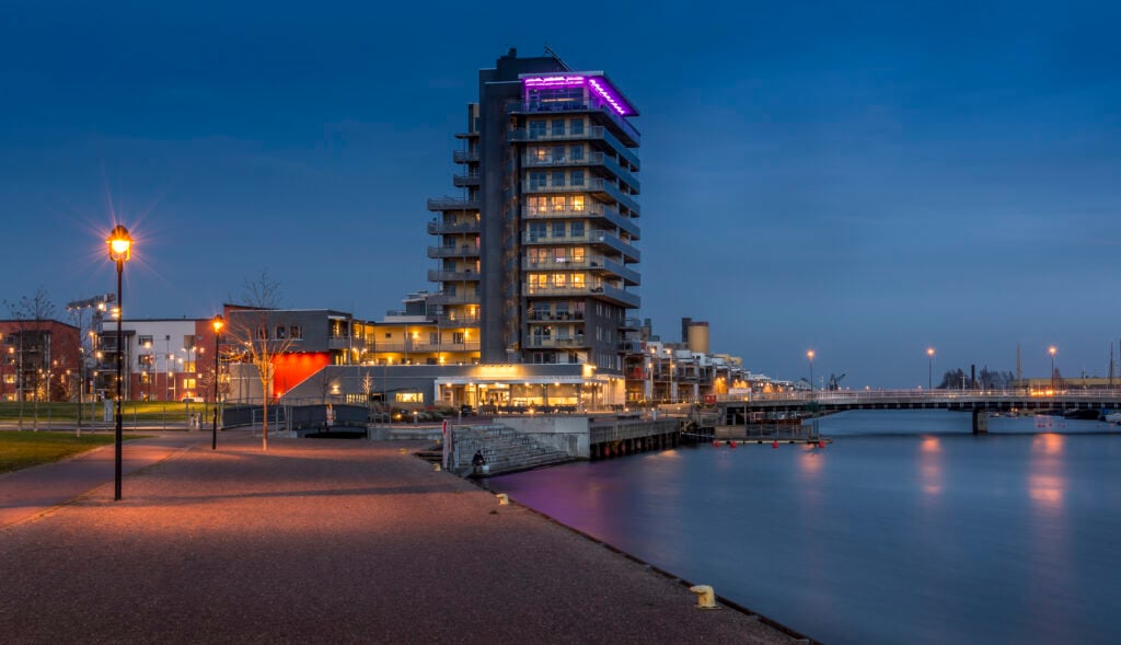 Höga hus och en kajkant i dunklet. 