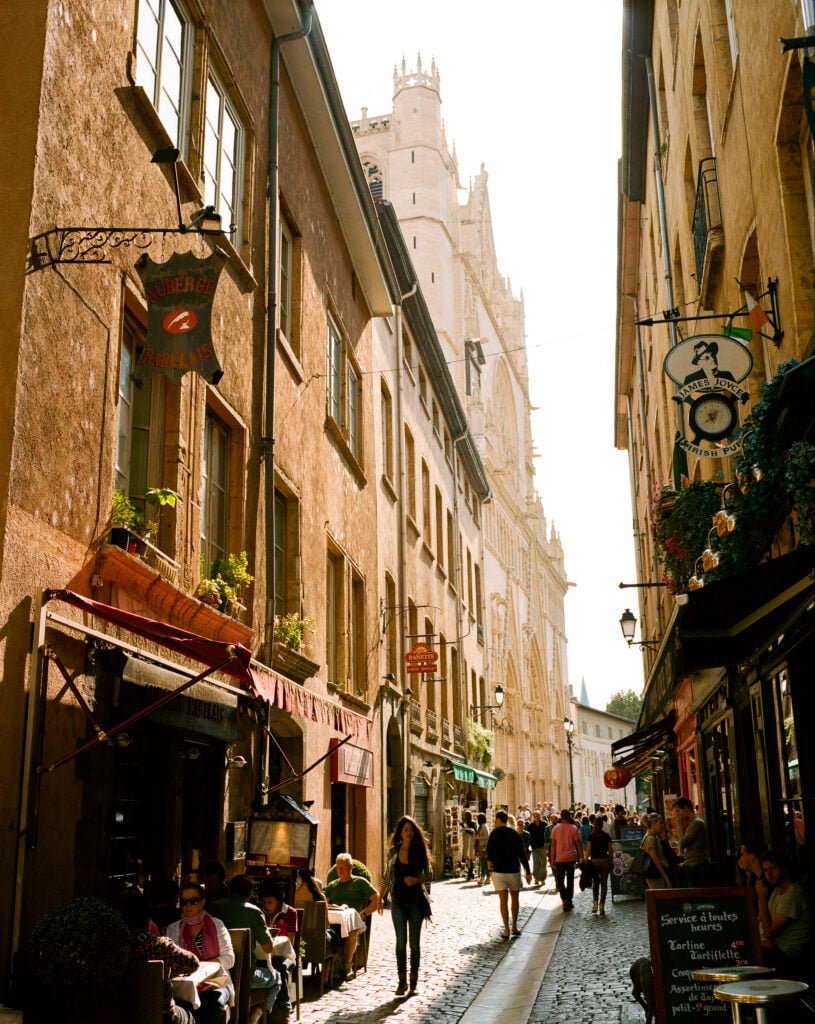 France, Rhone-Alpes, Lyon, Crowded narrow cobbled street lined with restaurants and bars with late afternoon sunshine