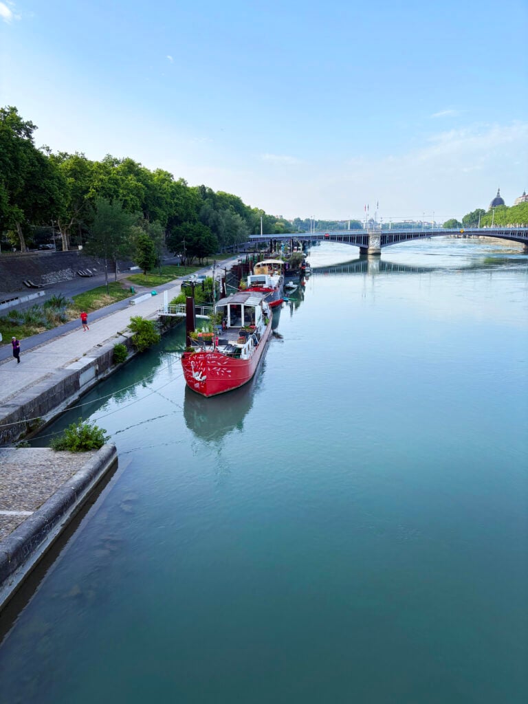 En flod med en kaj, röda flodskepp, en bro över floden. 
