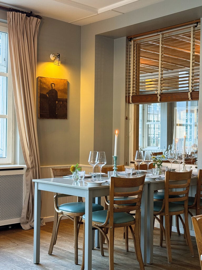 Ett vitt bord med trästolar med blå sitsar. 