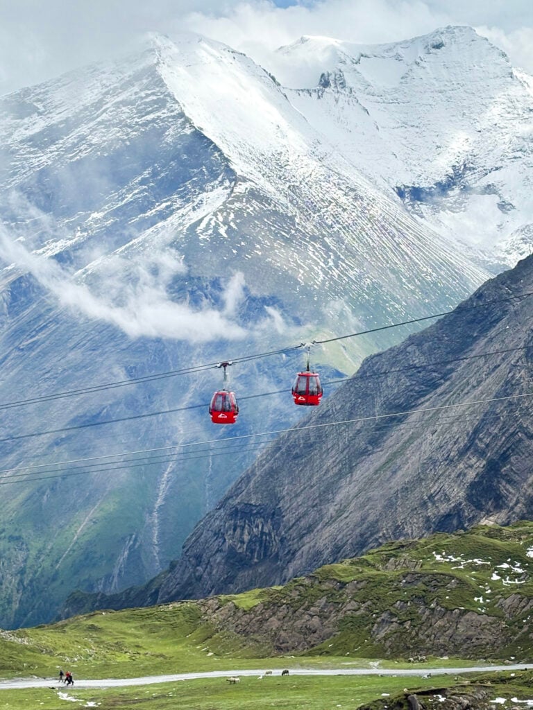 Två små röda gondoler hänger mellan dramatiska berg. 