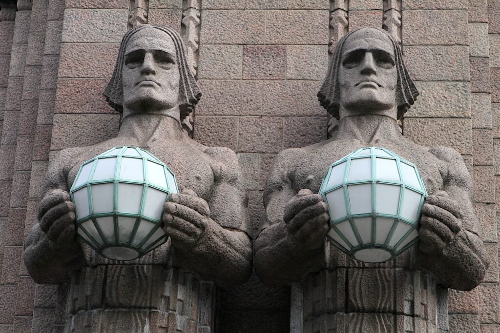 Två grå stenstayer som håller lyktor i handen
