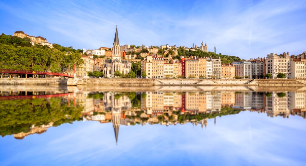 Ett stadslandskap med en kyrka speglas i floden.
