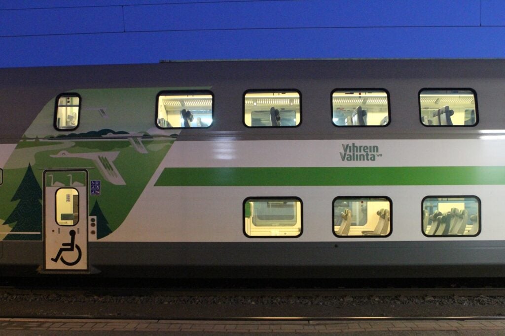 Dubbeldäckat nattåg mitt i natten stående vid en perrong.