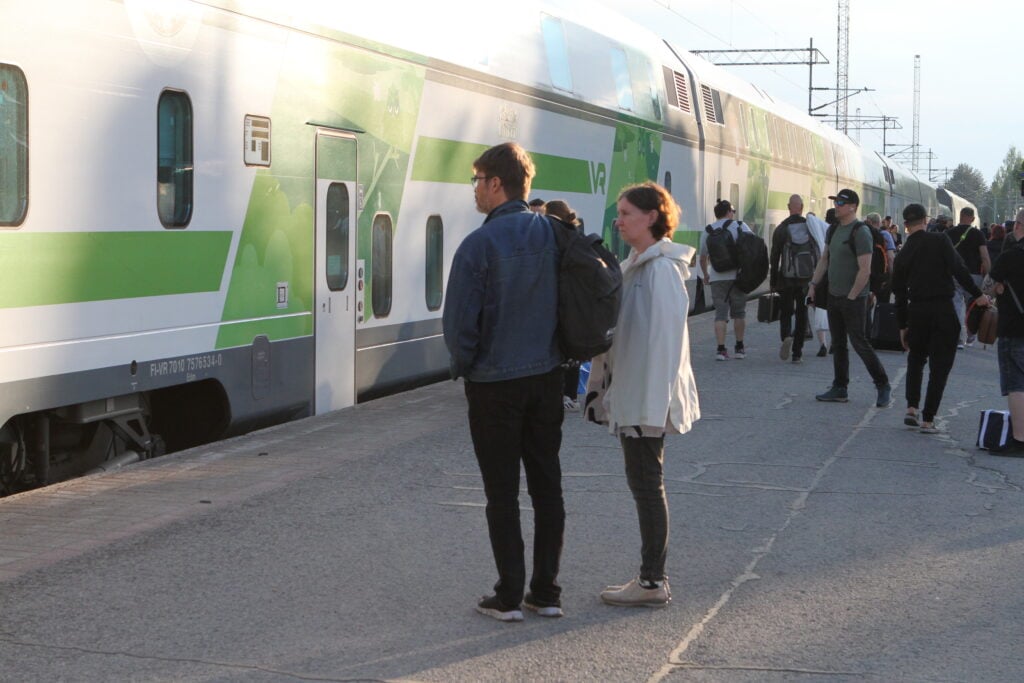 tåg vid perrongen med resenärer som väntar.